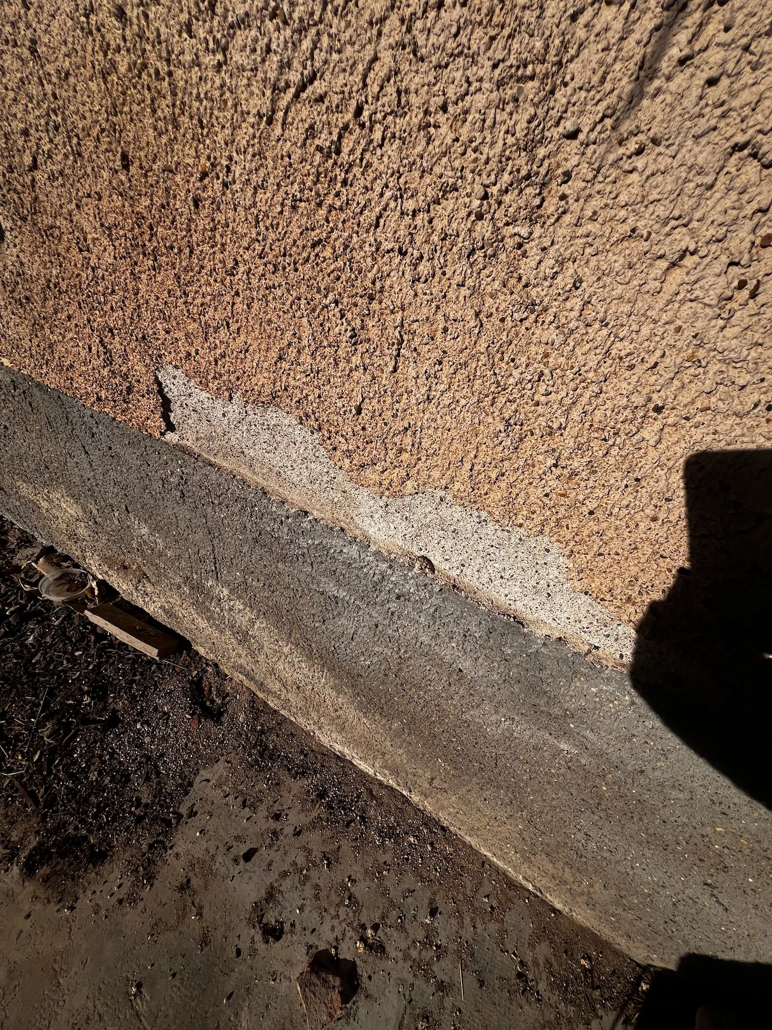 Soubassement d'une maison en pisé recouvert d'enduit ciment