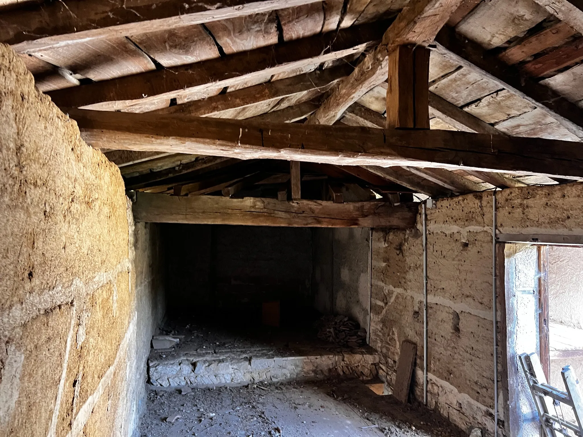 Intérieur d'une ferme en pisé avec murs bruts et charpente d'origine 1880