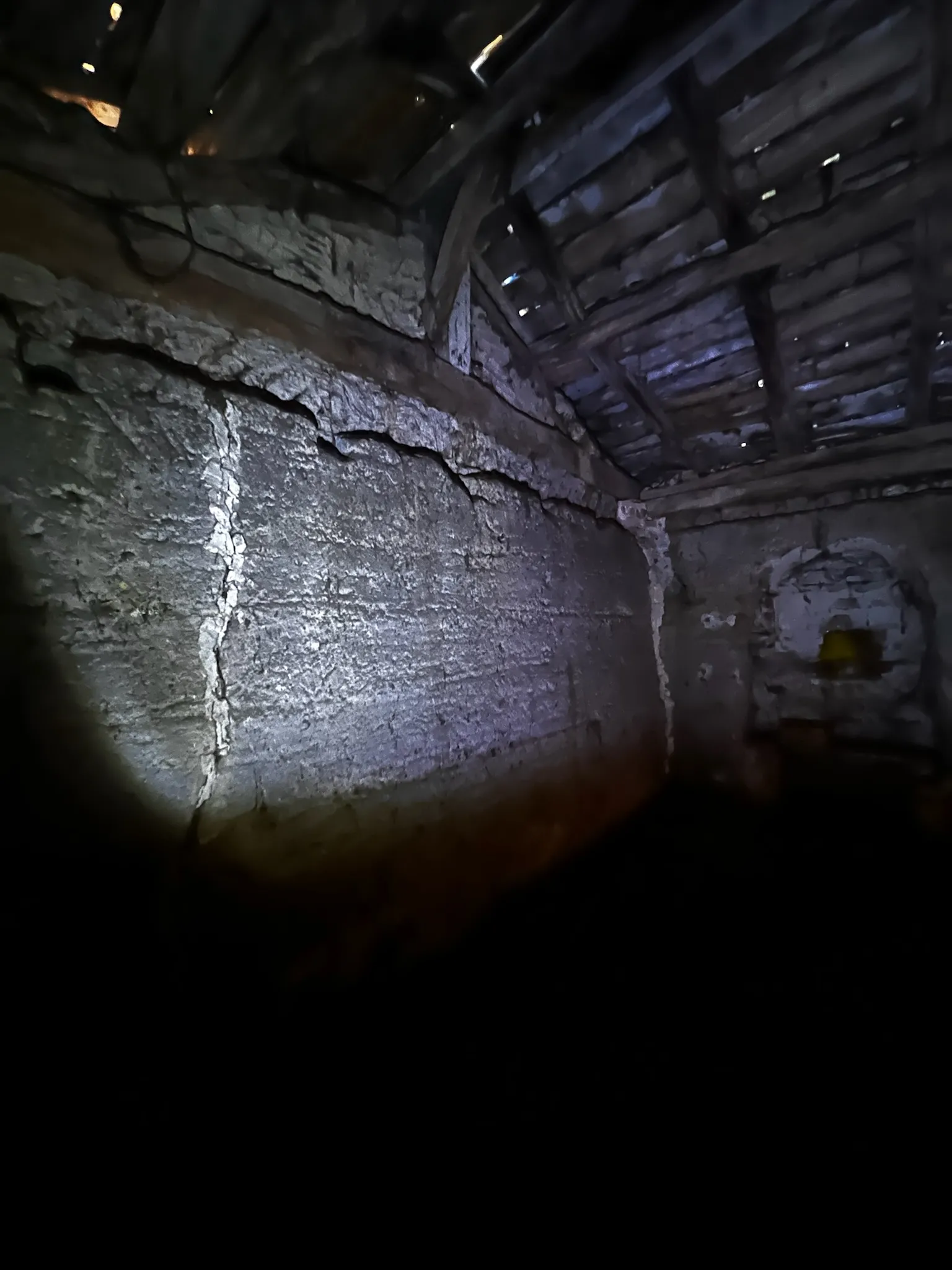 Charpente où l'on voit la lumière du jour à travers et les dégâts sur le mur en pisé