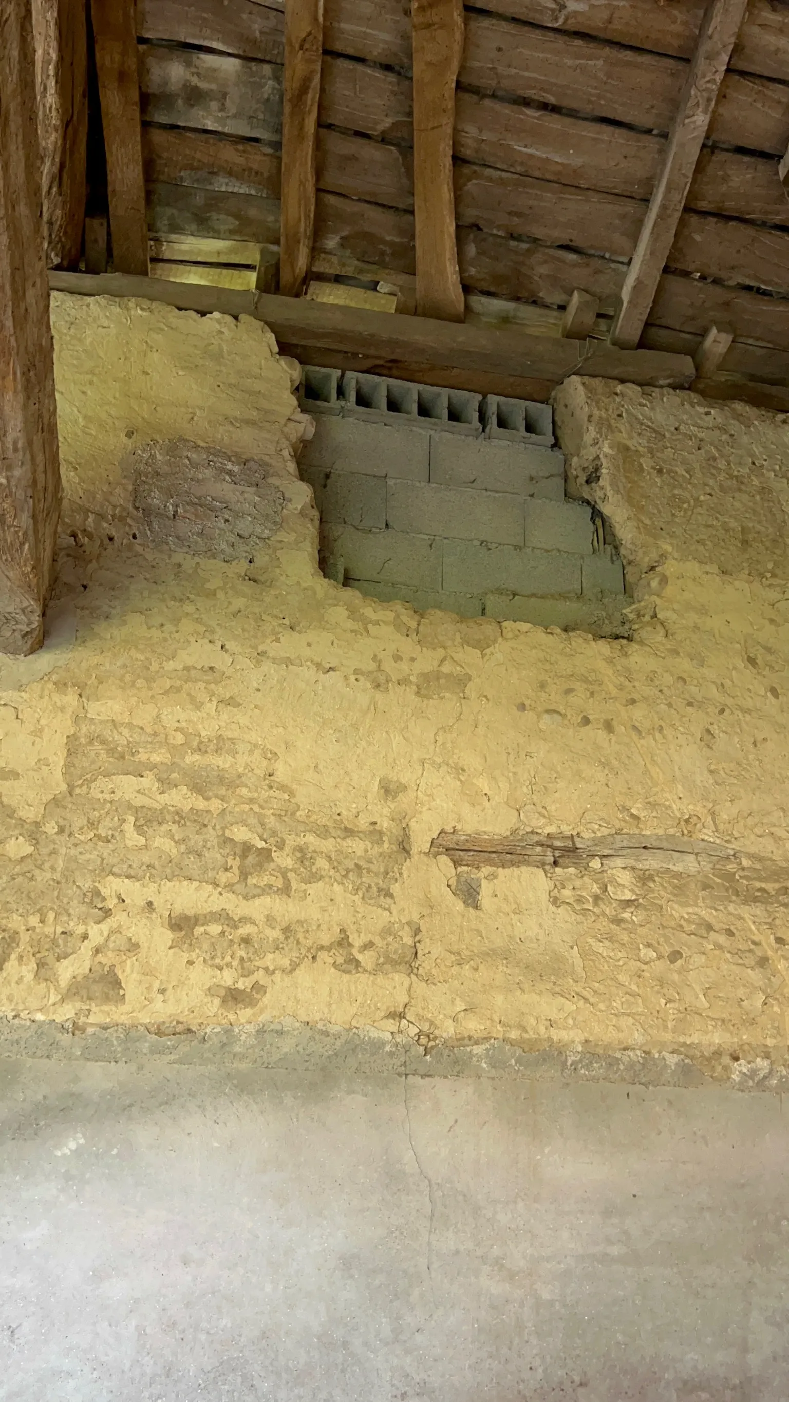 Mauvaise réparation dans une ferme avec Enduit Ciment en bas et Parpaing en haut ayant entraîné une fissure malgré l'agrafe en bois